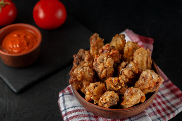 Buffolo wings close-up in ceramic bowl with tomato sauce and tomatoes