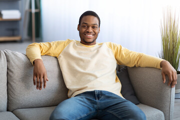 Handsome black man sitting on sofa at home