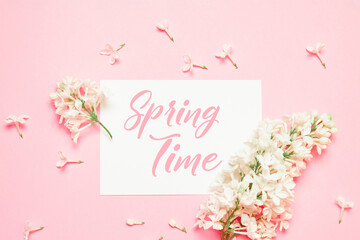 Spring time. White flower lilac branch and paper template blank on pink background. Flat lay, top view.