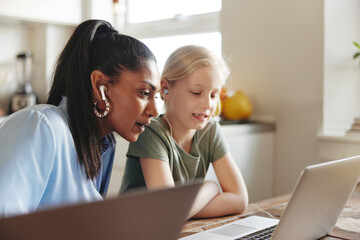 Little girl and her mom watching something on a laptop