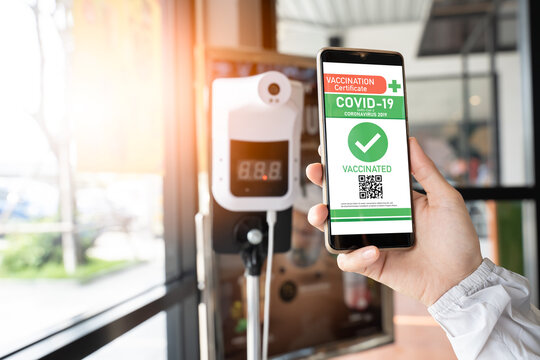 Vaccination passport certification,Immunity e-passport concept.Hand holding smartphone to show coronavirus(Covid-19) vaccination certificate application for check-in location at coffeeshop.