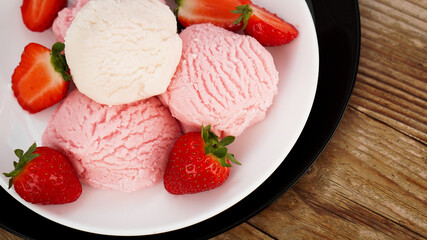 Delicious strawberry ice cream with fresh strawberrieson a white and black plate
