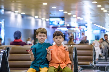 Two young brother boy dreaming of becoming a pilot. A child with a toy airplane plays at airport waiting for departure on their aircraft. Travel and holidays with children concept