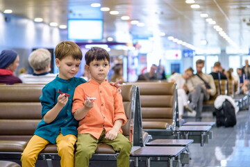 Two young brother boy dreaming of becoming a pilot. A child with a toy airplane plays at airport waiting for departure on their aircraft. Travel and holidays with children concept