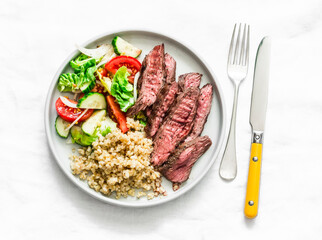Balanced lunch - medium roast steak, vegetable salad and bulgur on a light background, top view