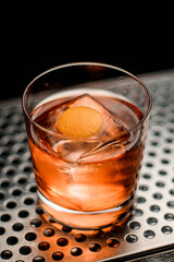 close-up of glass with drink and ice cube on steel surface of bar counter