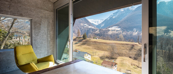 Interior of a beautiful modern house, where you see a table, a yellow armchair and a view of nature