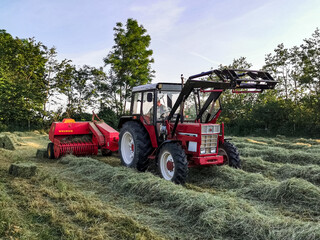 tractor in field pressing packs of hay in northern Germany, Schleswig Holstein.