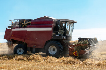 combine harvester while working in the field with wheat during the harvesting campaign. Combine harvesting the wheat field. The harvest season of grain crops.
