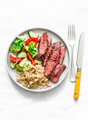 Balanced lunch - medium roast steak, vegetable salad and bulgur on a light background, top view