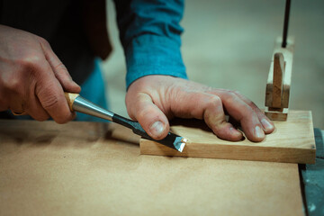 a man makes furniture, cutting details with tools