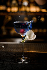 view on transparent glass with splashing blue drink and decorated with white flower