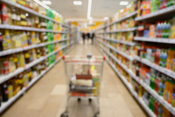 Shelves and cart in supermarket as blurred background. Shopping concept.