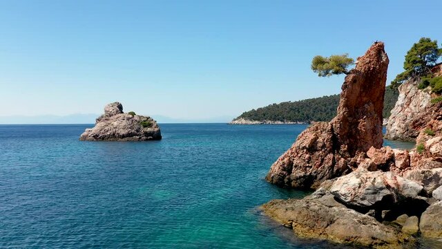 Aerial drone views over a rocky coastline, crystal clear Aegean sea waters, touristic beaches and lots of greenery in Skopelos island, Greece. A typical view of many similar Greek islands.