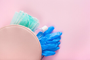 protective medical mask, sanitizer gel and gloves in pink bag. protective measures against virus, bacteria