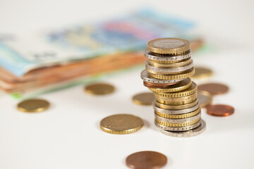 Stack of euro coins on table with paper notes in background