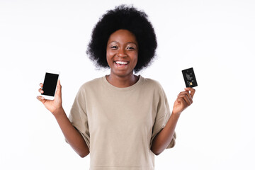 Fototapeta Cheerful african girl holding smart phone and credit card isolated in white obraz