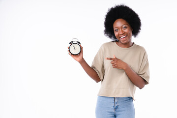 Happy teenager girl african-american pointing at the clock isolated in white background