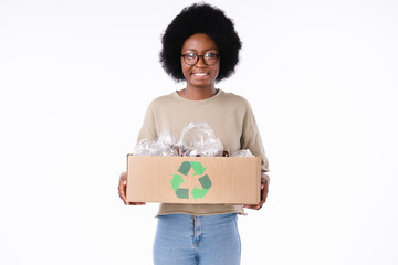 Happy eco-friendly african teen girl holding a box full of plastic bottles for recycling isolated...