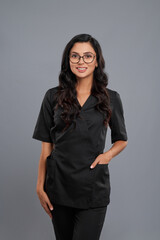 Smiling cosmetologist in eyeglasses posing in studio