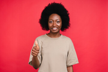 Happy african-american teen girl showing thumb up isolated in red