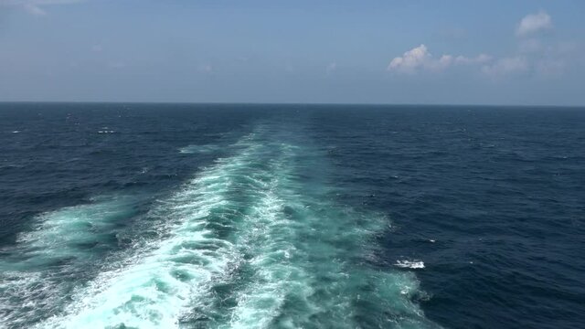 Sailing on Atlantic ocean under cloudy blue sky and leave foam behind the boat.