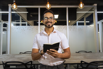 Retrato de hombre joven sonriente escribiendo notas en cuadernillo