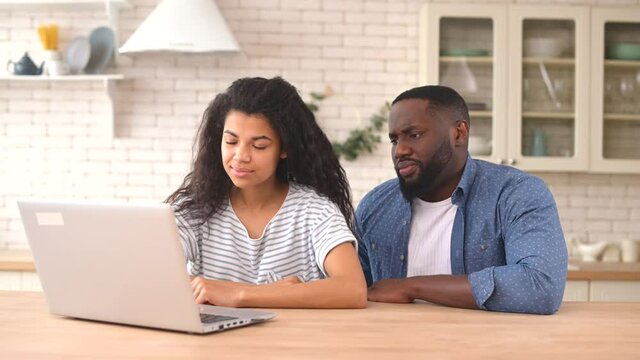 Young African-American couple has financial problem, a frustrated wife and upset husband look through bills on the laptop, young multiracial spouses unable to pay for the mortgage