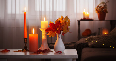 burning candles with autumn decor on white table at home