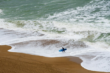 Jeune surfeur sortant de la mer après une séance de surf