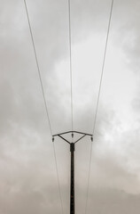Three wires concrete electrical pole, symmetrical composition, cloudy sky. France