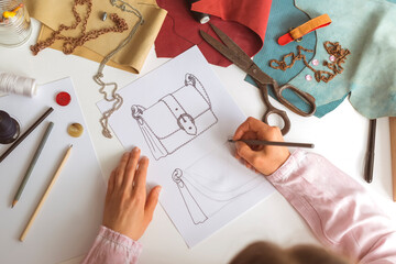 The designer draws a sketch of a woman's bag on paper at the workplace. Fashion design.