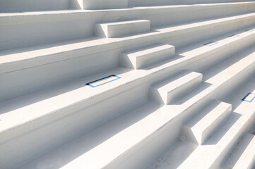 White stairway of a stadium with sunlight and nobody.
