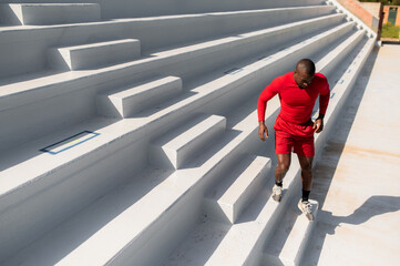 view from above black athletic man running up the stairs.