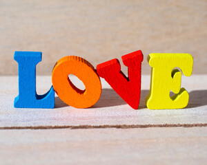 The word LOVE spelt with multi-colored wooden letter tiles.