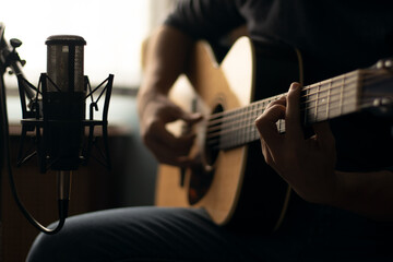 Man playing acoustic guitar and recording with a microphone