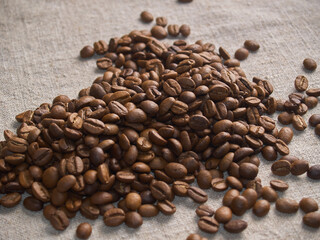 Roasted coffee beans scattered on a burlap napkin.