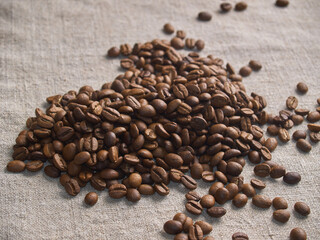 Roasted coffee beans scattered on a burlap napkin.