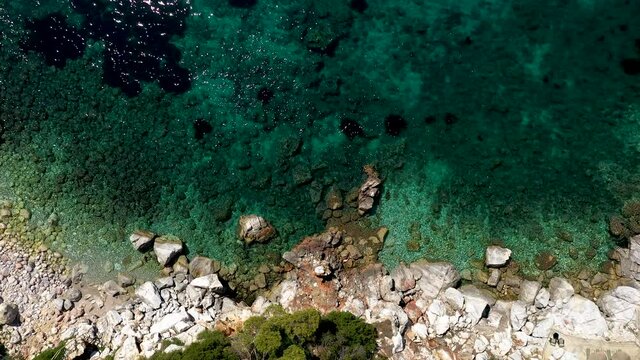 Aerial drone views over a rocky coastline, crystal clear Aegean sea waters, touristic beaches and lots of greenery in Skopelos island, Greece. A typical view of many similar Greek islands.
