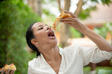 Hungry middle-aged women eat pizza like crazy for a delicious meal.