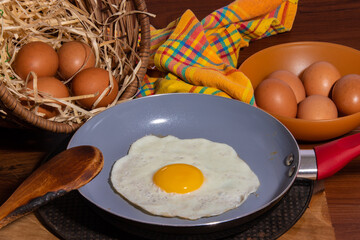 Fried egg in a frying pan with eggs complementing the farm scene on a wooden table