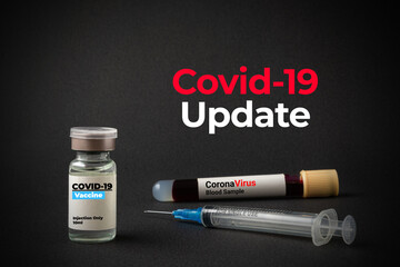 COVID-19 UPDATE text with a bottle of vaccine, sample blood vacuum tube and syringe on black background. Covid-19 or Coronavirus Concept.