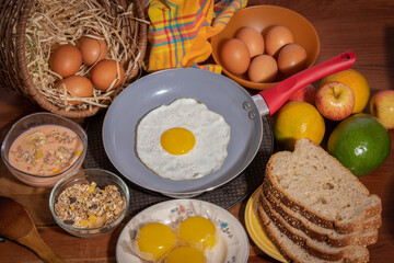 Farm breakfast with fruits, breads, eggs, yogurt, cereals on wooden table seen from above