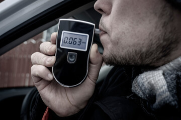 a man with a breathalyzer in the car