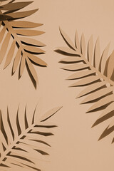 Paper hand cut tropical palm leaves on the beige background. Summer concept Top view