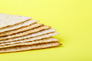 Square matzo several sheets one on top of the other on a yellow background.