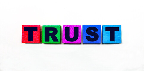 The word TRUST is written on colorful cubes on a light background