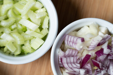 deux petits bols blancs remplis d'oignons rouges et blancs et de céleri coupés