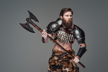 Warlike nordic warrior with an axe staring away in gray background