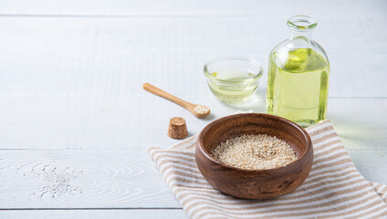 Natural vegetable oil from sesame seeds in a clear bottle on the wooden background. Dietary healthy food